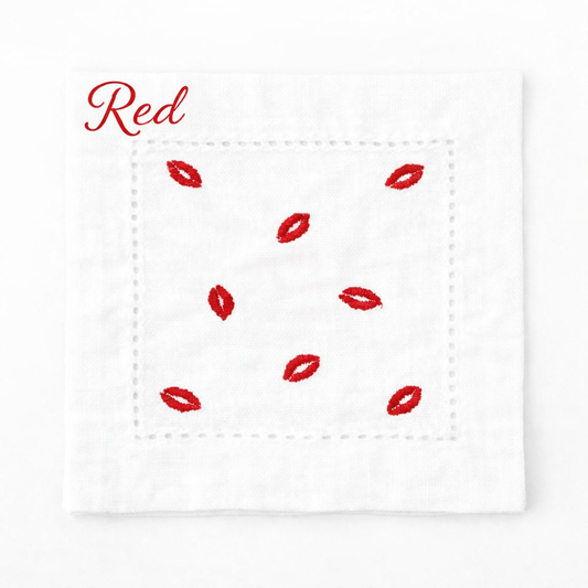 Embroidered white cocktail napkin featuring red kiss lip design, styled for Valentine’s Day table décor, romantic dinner parties, and chic entertaining.